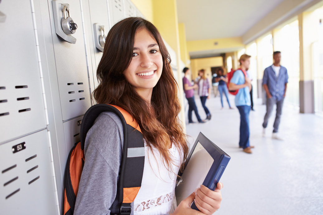 Student standing by lockers in a bright school hallway