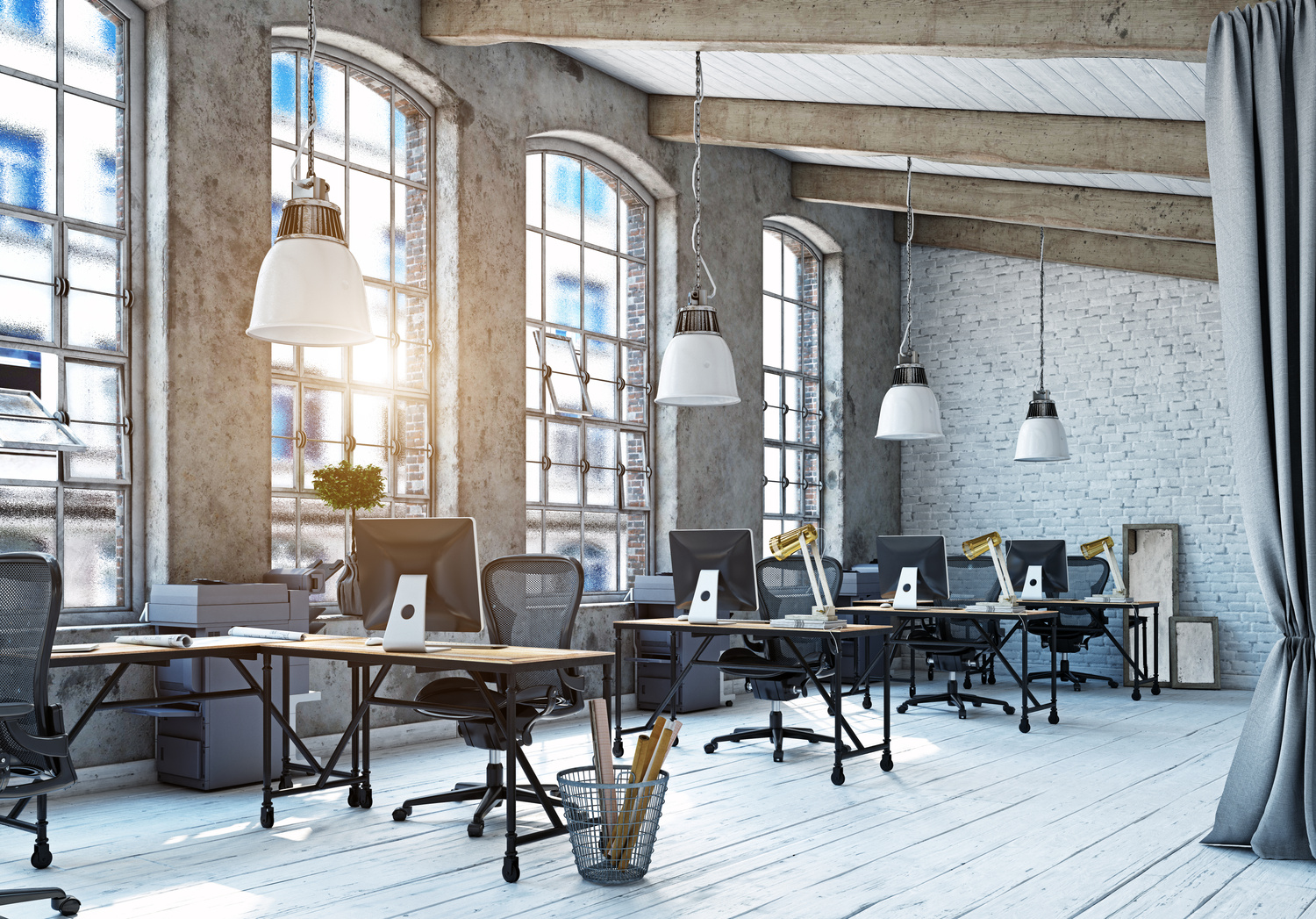 Industrial-style open office with desks, monitors, arched windows, and concrete beams